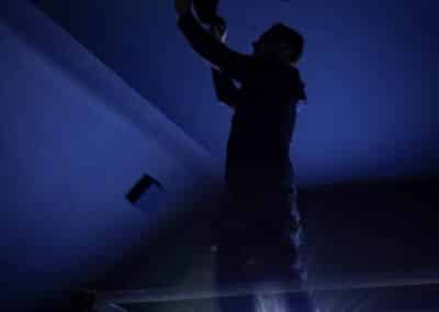 Silhouette of an installer fitting fibre-optic star ceiling lighting in the Wynyard Park home cinema.